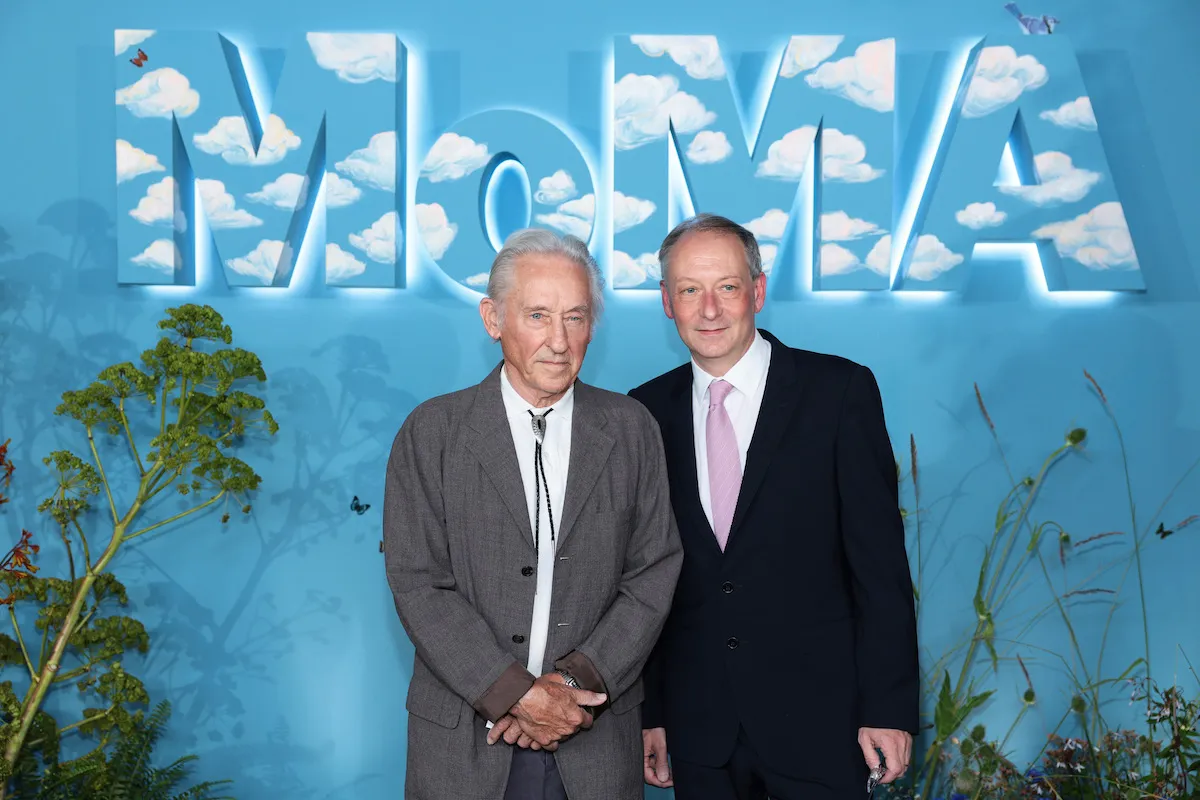 Two men standing beneath the MoMA logo.