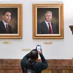 DENVER, CO - MARCH  24: A  visitor takes a picture of the portrait of president Donald Trump, right, that hang on walls in the rotunda on the third floor  of the Colorado State Capitol  in Denver, Colorado on March 24, 2025. The portraits of Presidents Barack Obama, left,  and Donald Trump were painted by Sarah A. Boardman. Boardman painted Trump