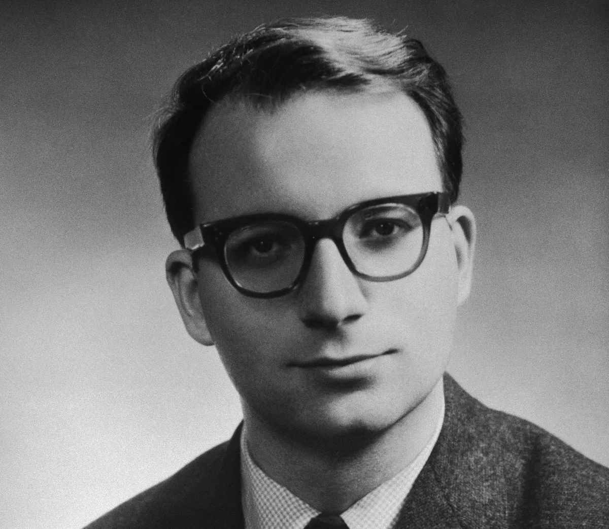 A black-and-white photograph of a man in a suit wearing glasses.