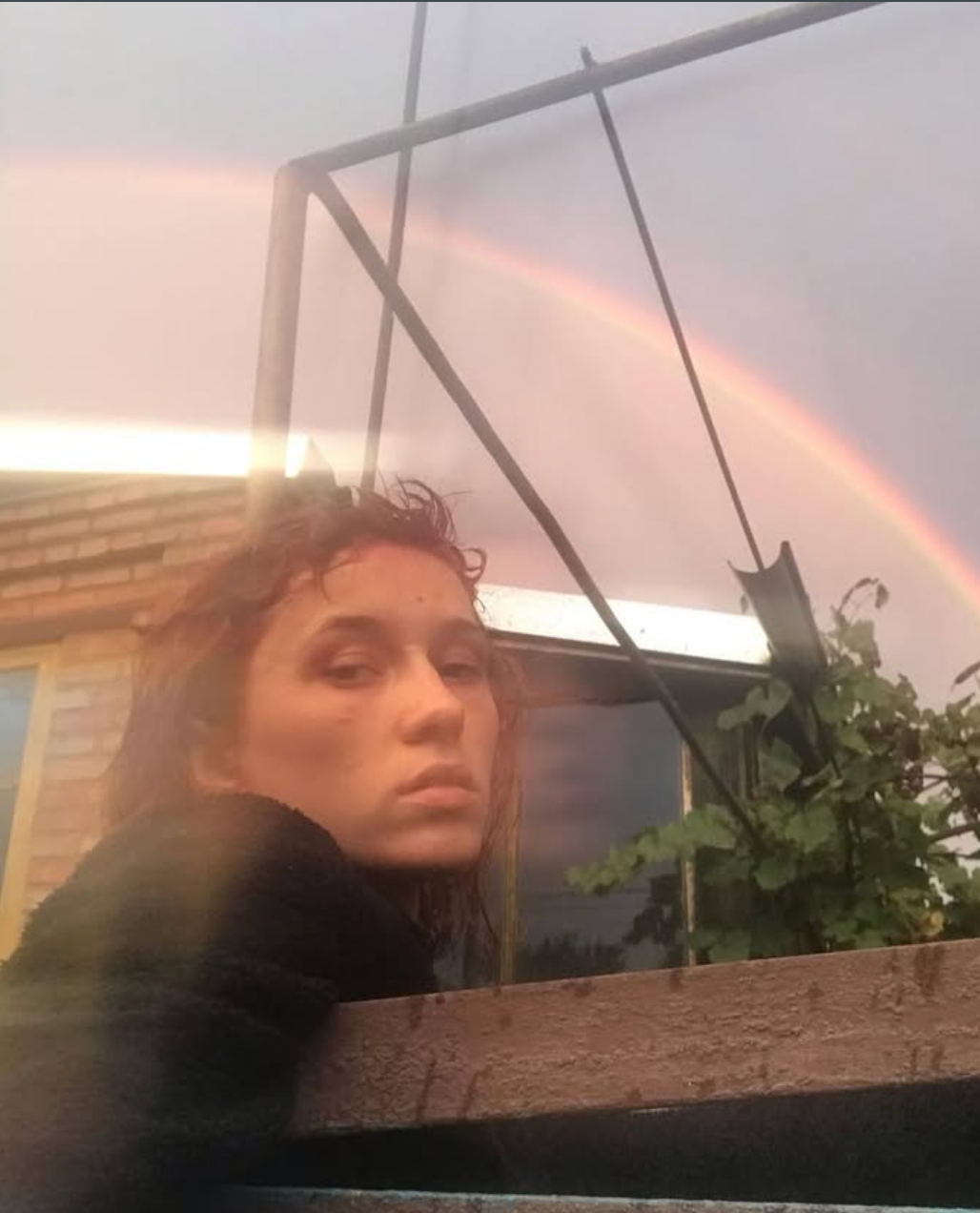 A woman is in front of a rainbow