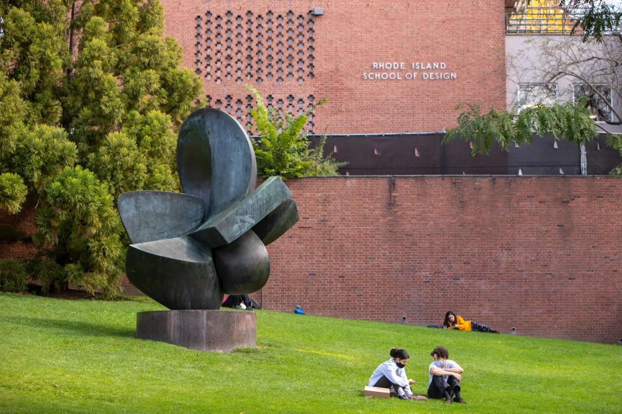 Students sit on a lawn next to a large sculpture on the campus at the Rhode Island School of Design.