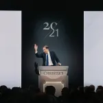 A man stands at a rostrum taking a bid.