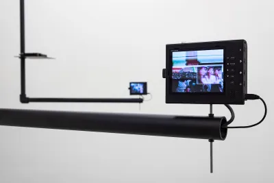 A small monitor showing a group of people attached to a metal bar.