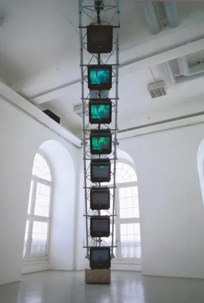 A tower of TV screens suspended in a gallery.