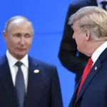 Two men in suits look at each other.