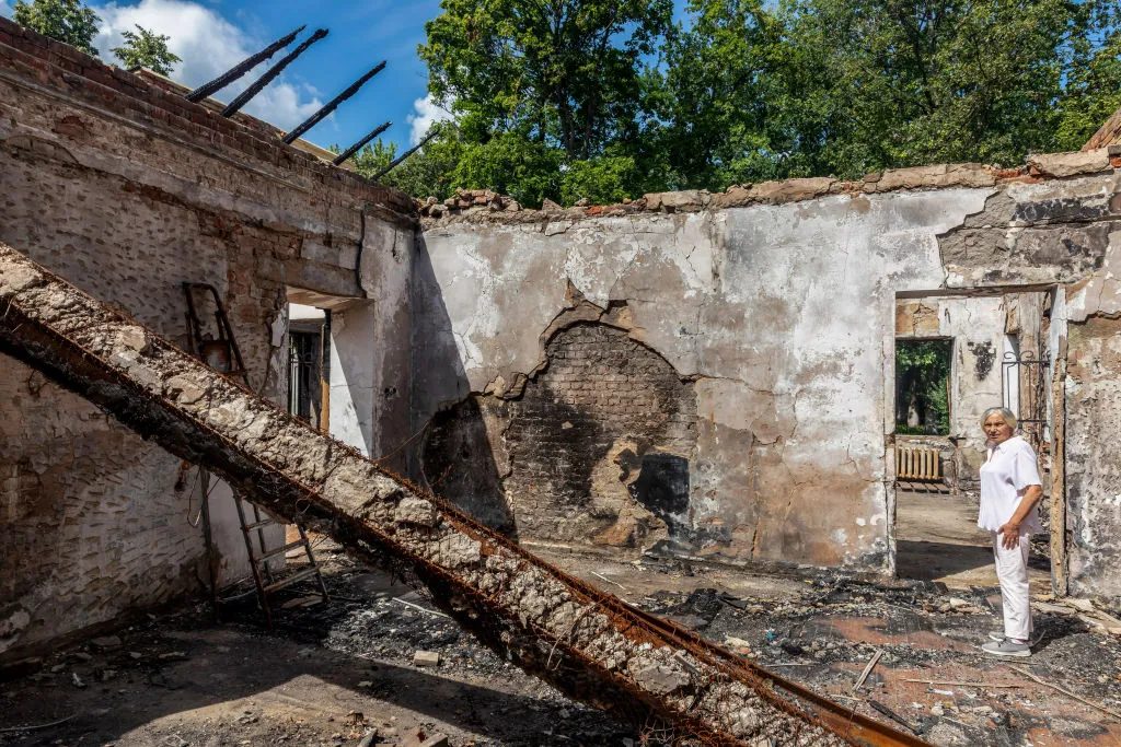 A man stands in the ruin of a bombed house in Ukraine.