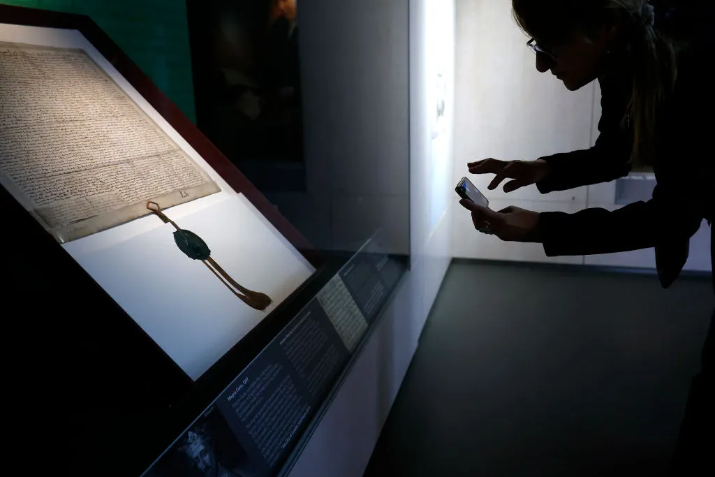 LONDON, ENGLAND - SEPTEMBER 20: A museum visitor takes a photograph of The City of London Corporation’s 1297 copy of Magna Carta on display at its Heritage Gallery within Guildhall Art Gallery on September 20, 2022 in London, England.