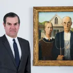A man in a suit standing next to a painting of a farmer with a pitchfork beside a woman in front of a house.