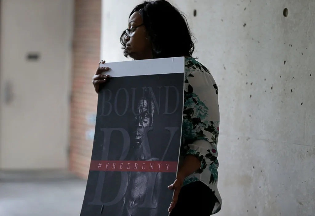CAMBRIDGE, MA - JUNE 20: Shonrael Lanier, a descendant of former slave Renty Taylor, holds a sign at a press conference held at Harvard University to talk about the lawsuit that the family has filed against the university in Cambridge, MA on June 20, 2019. Under cover from a torrential downpour, two families came together on Harvard Universitys campus Thursday to demand that the institution turn over historical photographs of two slaves and reckon with its history of white supremacy. Tamara Lanier, a Connecticut woman who sued Harvard in March, has said shes a descendant of Renty and his daughter Delia, two slaves who were forced in 1850 to pose naked for daguerreotypes, or early photographs. She said the images, discovered in 1976 and stored in Harvards Peabody Museum, rightfully belong to her, and her lawsuit alleges that Harvard is shamelessly capitalizing on them. She was joined at a press conference Thursday by descendants of controversial Harvard scientist Louis Agassiz, who commissioned the daguerreotypes in an attempt to support his theory of white biological superiority. (Photo by Jonathan Wiggs/The Boston Globe via Getty Images)