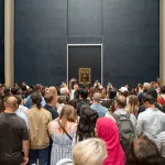 A crowd of people before a painting.