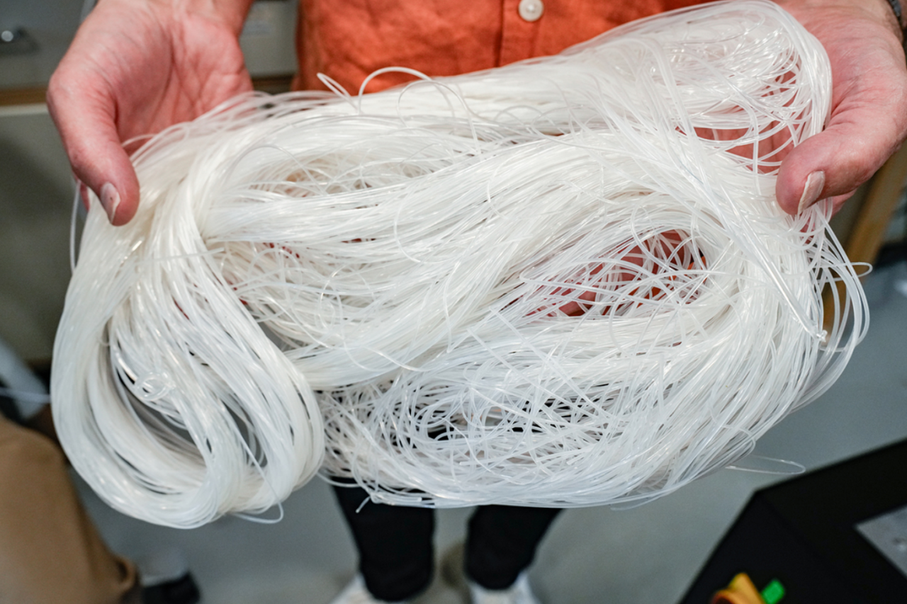 Someone holding long thin strips of white plastic.
