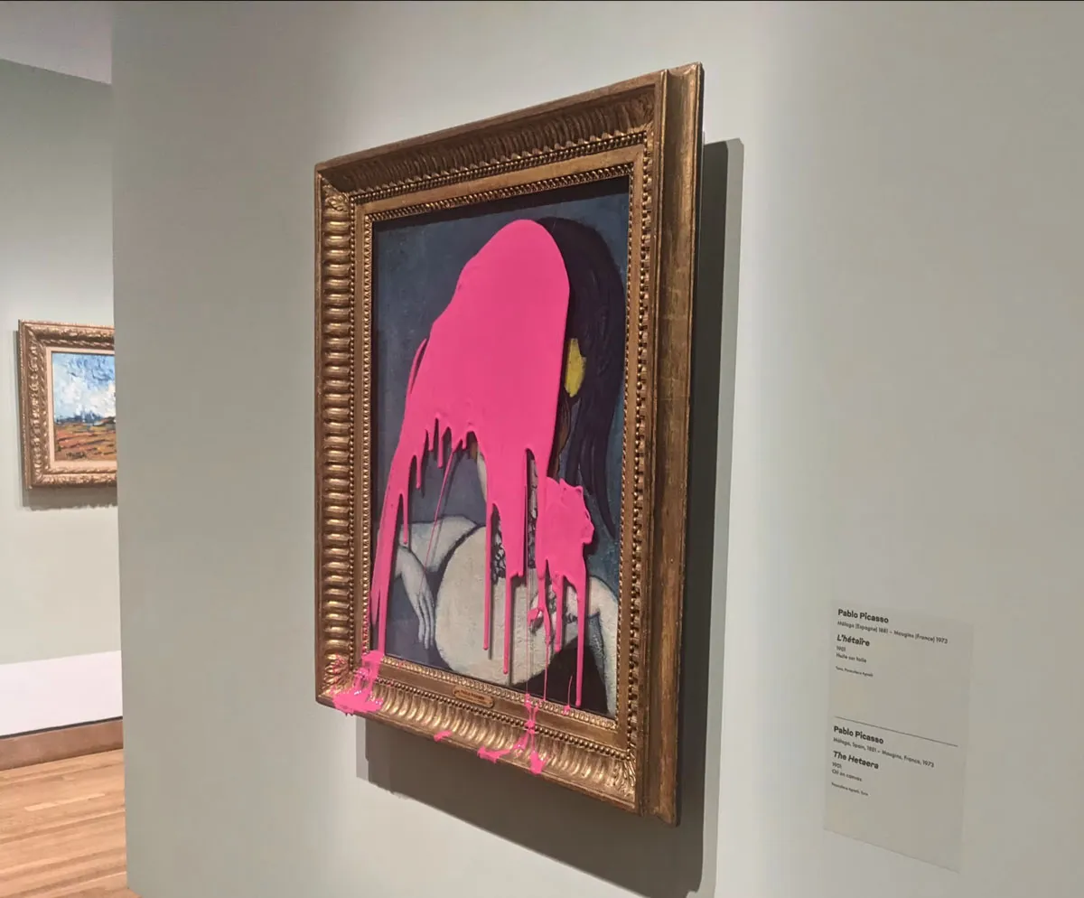 A painting in a gold frame is covered with a large glob of hot pink paint so that most of the portrait is now obscured.