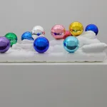 A marble sculpture of a sleeping figure covered with colorful highly polished orbs.