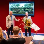 A man receives flowers in front of a recovered Van Gogh painting.