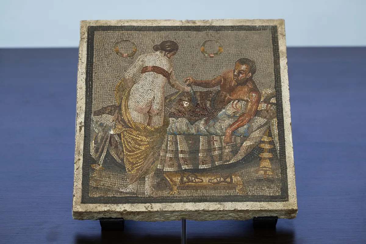 A mosaic showing a nearly nude woman reaching toward a reclining man.