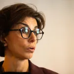 A woman wearing glasses with brown hair.
