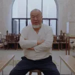 Ai Weiwei sits on a stool in his studio.