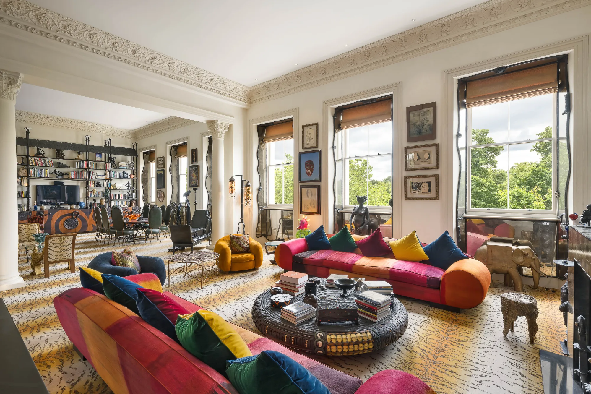 a room with large windows, sofas, and many paintings on the wall.