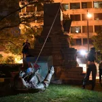A group of people toppling a monument.