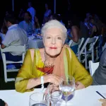 A woman in a dress leaning over a table at a party.