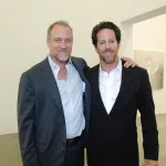 Two men in suit jackets in a gallery.