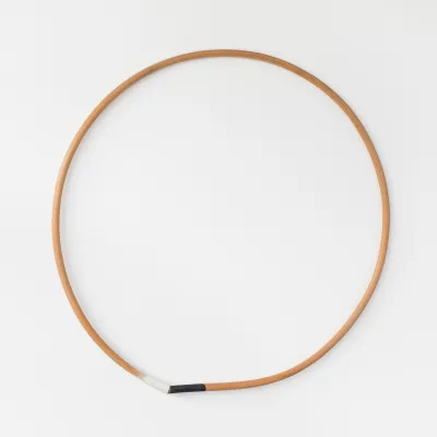 A wood circle with one portion at the bottom painted white and another painted black.