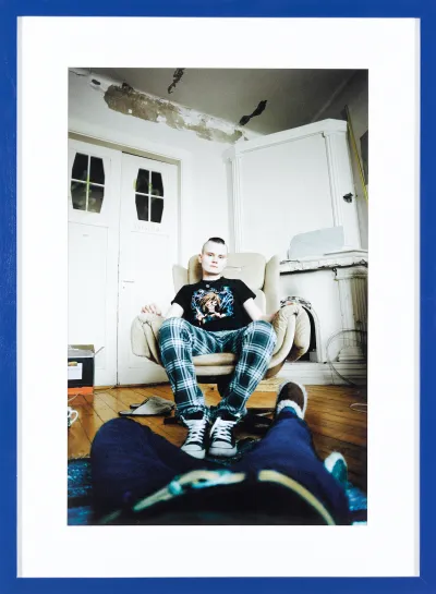 A photograph of a woman sitting in a chair taken by a photographer lying on the floor. The photographer