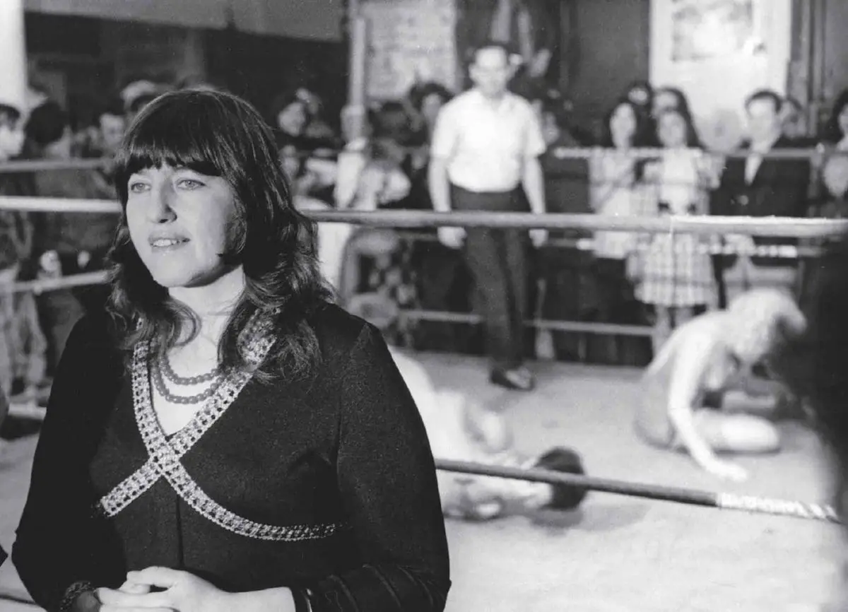 A woman standing next to a boxing ring.