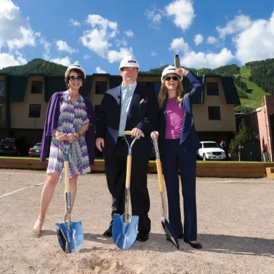 Three people holding shovels at a groundbreaking. 