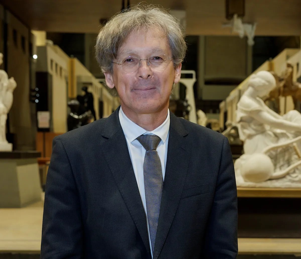A man in a suit standing in an exhibition hall.