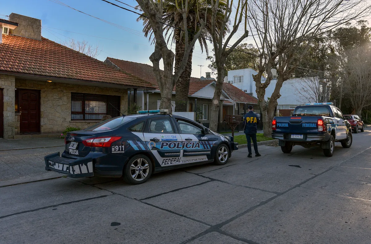 Two police cars in front of a set of houses.
