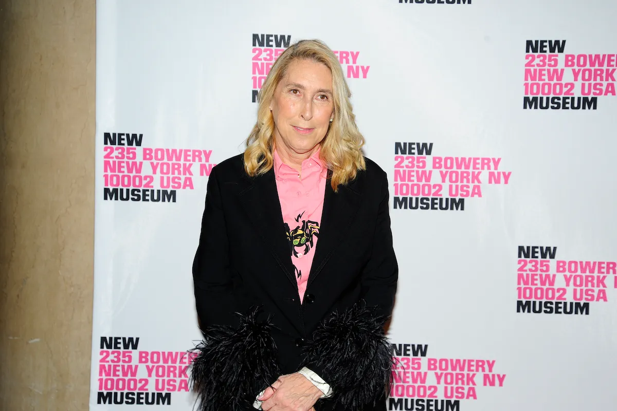 A woman standing on a red carpet with her hands clasped.