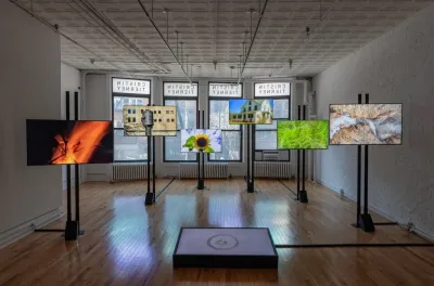 View of an installation showing six screens that are at different heights and staggered around the gallery. 