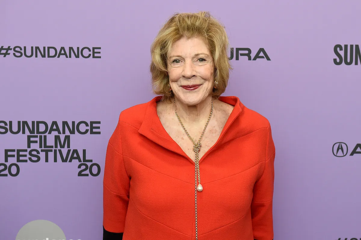 A woman in an orange dress on a red carpet.