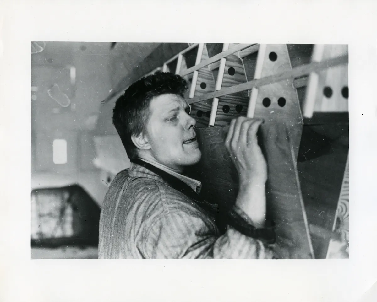 A man lifting a piece of wood and sticking out his tongue.