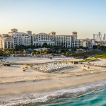 A grand building on a beach in front of the sea.