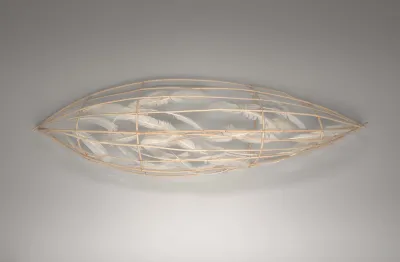 A wooden armature sculpted to resemble a canoe. The armature is filled with feathers.