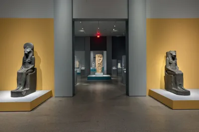 A gallery with two sculptures of seated gods on either side of a hallway.