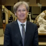 A man in a suit standing in an exhibition hall.