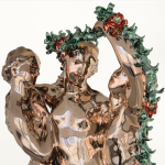 A detail shot of a shiny sculpture of three ladies and some garland.