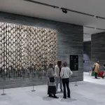 Installation view of a museum lobby showing people standing in front of an installation composed of reindeer skulls.