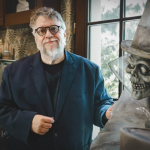 A bearded man next to a model of a skeleton head.