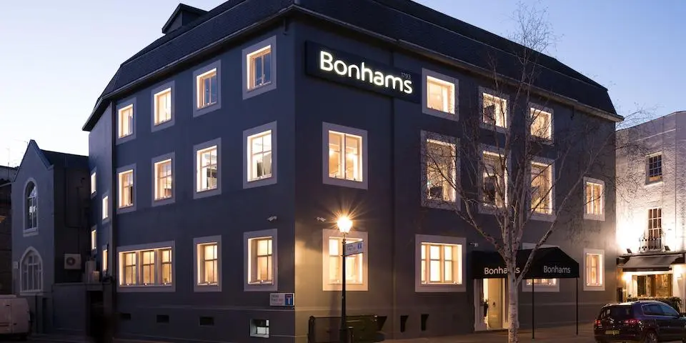 A building at night with lights shining through the windows.