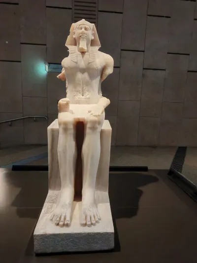 A statue of a seated Pharaoh that has its arms missing.