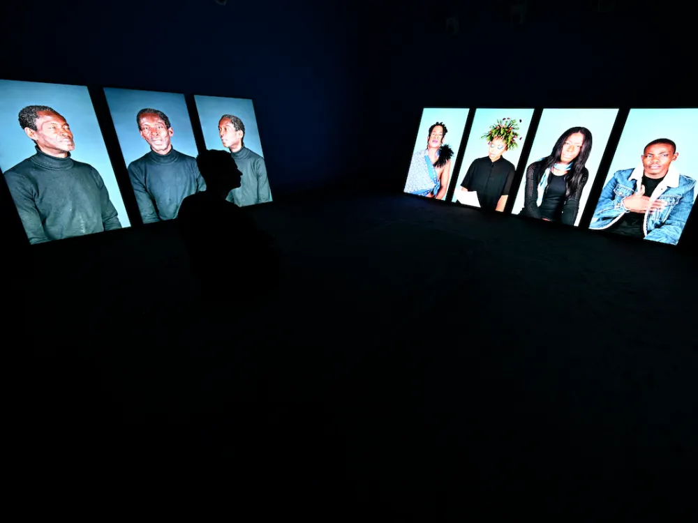 A person walking by multiple screens playing images of people.