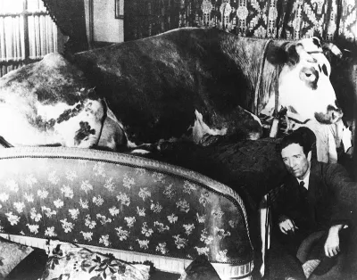 A painting of a man seated next to a bed with a cattle on it.