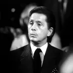 black and white photo of a man with dark hair and a suit and tie, looking somber