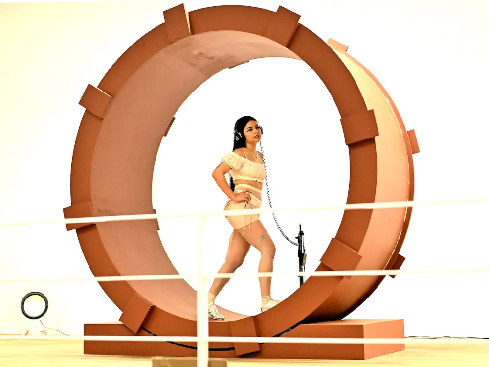 A woman with headphones walking in a spinning wheel.