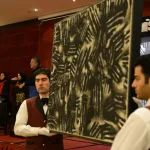 TEHRAN, IRAN - JUNE 28: A painting by one of the Iranian masters is held up for the spectators while the auctioneer and veiled aids conduct the auction in the dinning hall of Azadi Hotel on June 28, 2013 in Tehran, Iran. (Photo by Kaveh Kazemi/Getty Images)