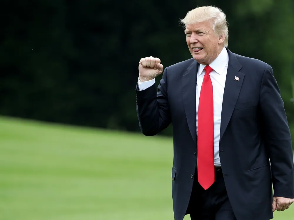 A man in a suit and red tie pumping his right fist.